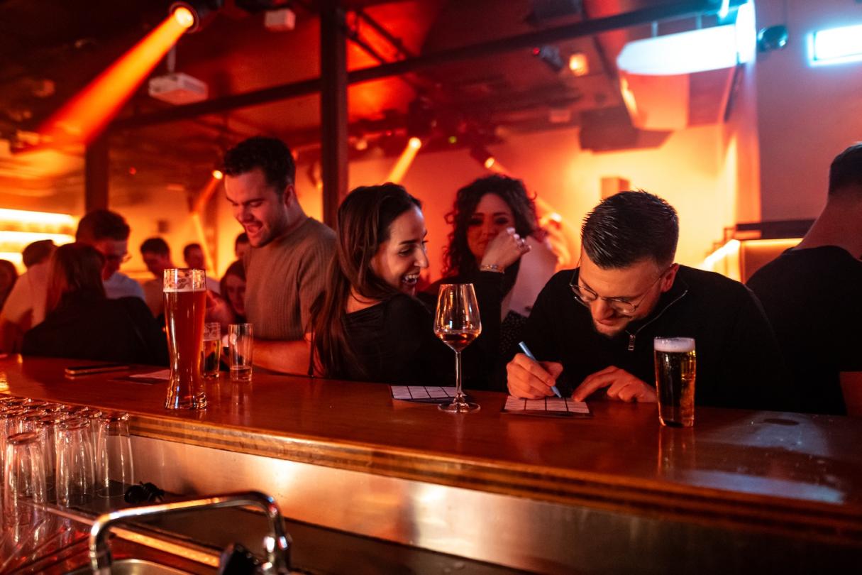 Friends filling in their bingo cards at the bar of a pub
